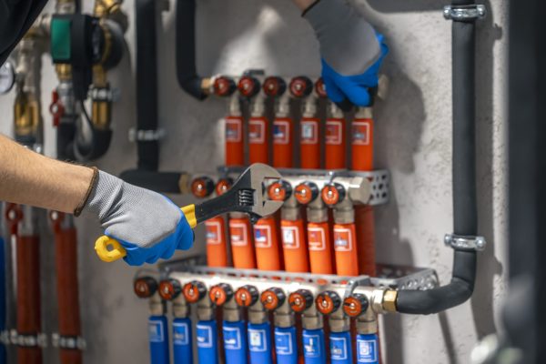 Adjusting heating valves in a residential building. A plumbing and heating technician works. Equipment for modern heating system as a boiler, heater,pipes, expansion tank and other