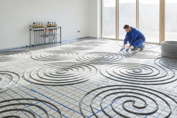 Underfloor heating pipes being laid across a concrete screed floor in a Tonbridge new build property